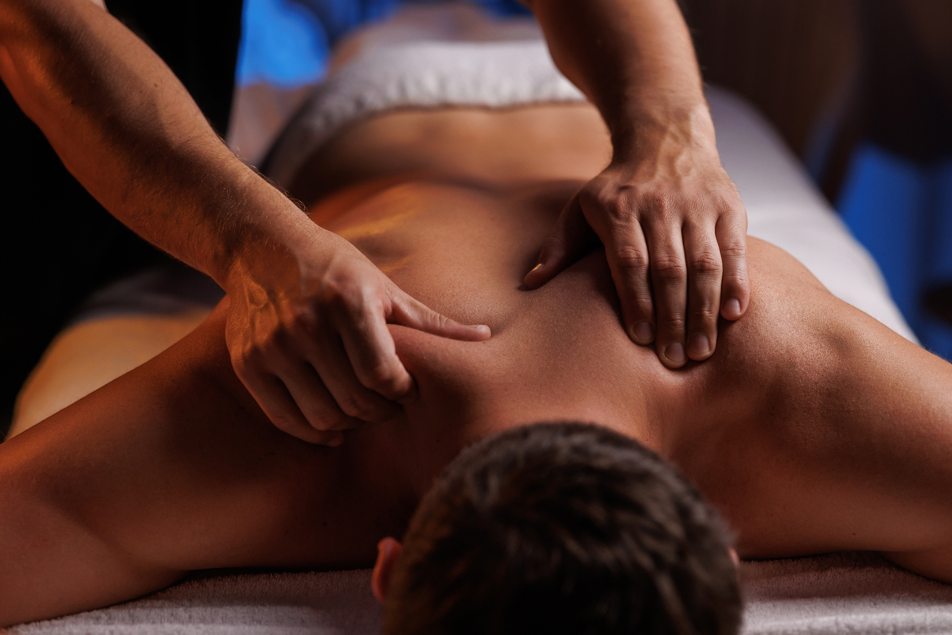 Professional sports massage therapy - hands working on client's back muscles
